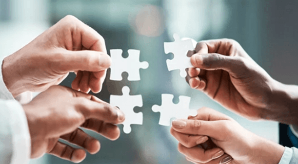 Four people connecting puzzle pieces together